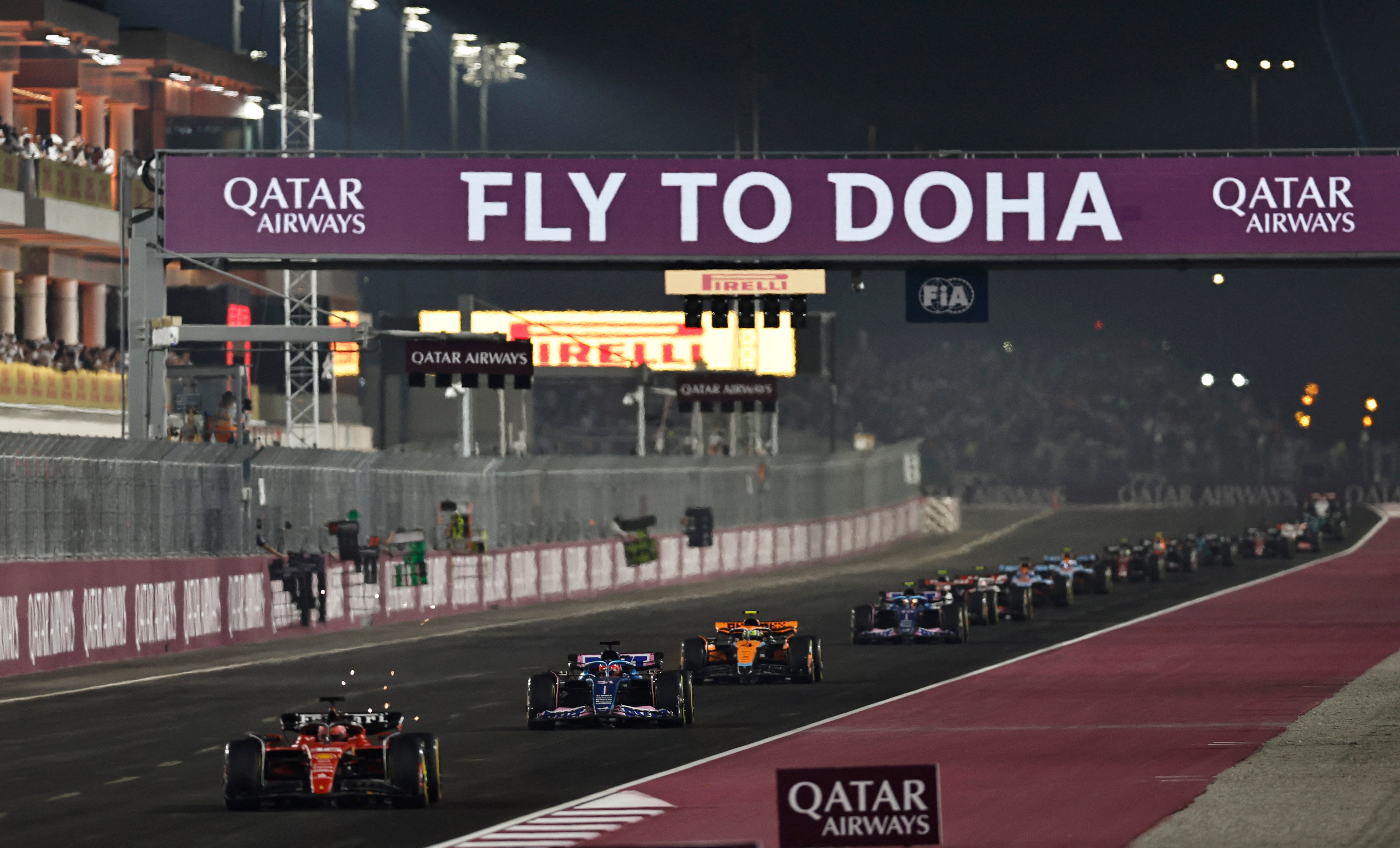 Formula 1 race cars on a track with Qatar Airways advertising at night