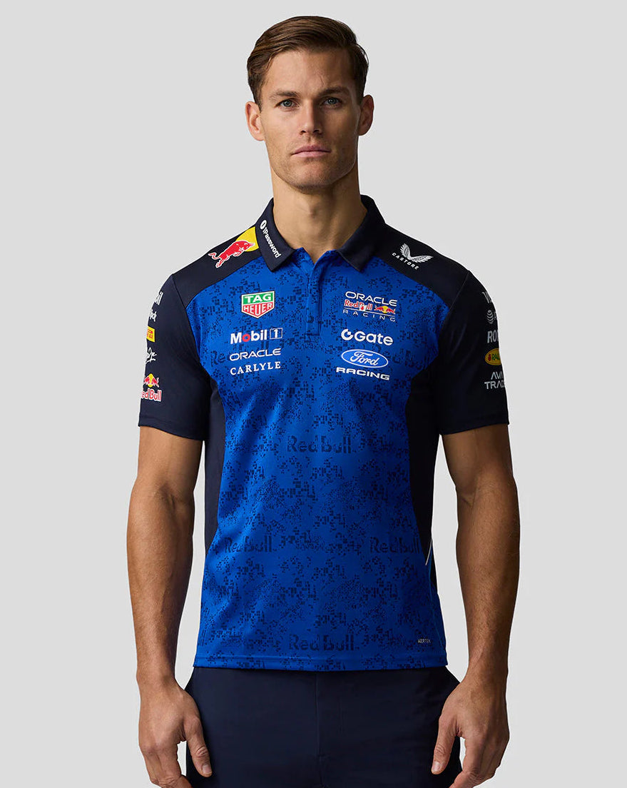 Man wearing a blue and black sports jersey with various sponsor logos on a gray background