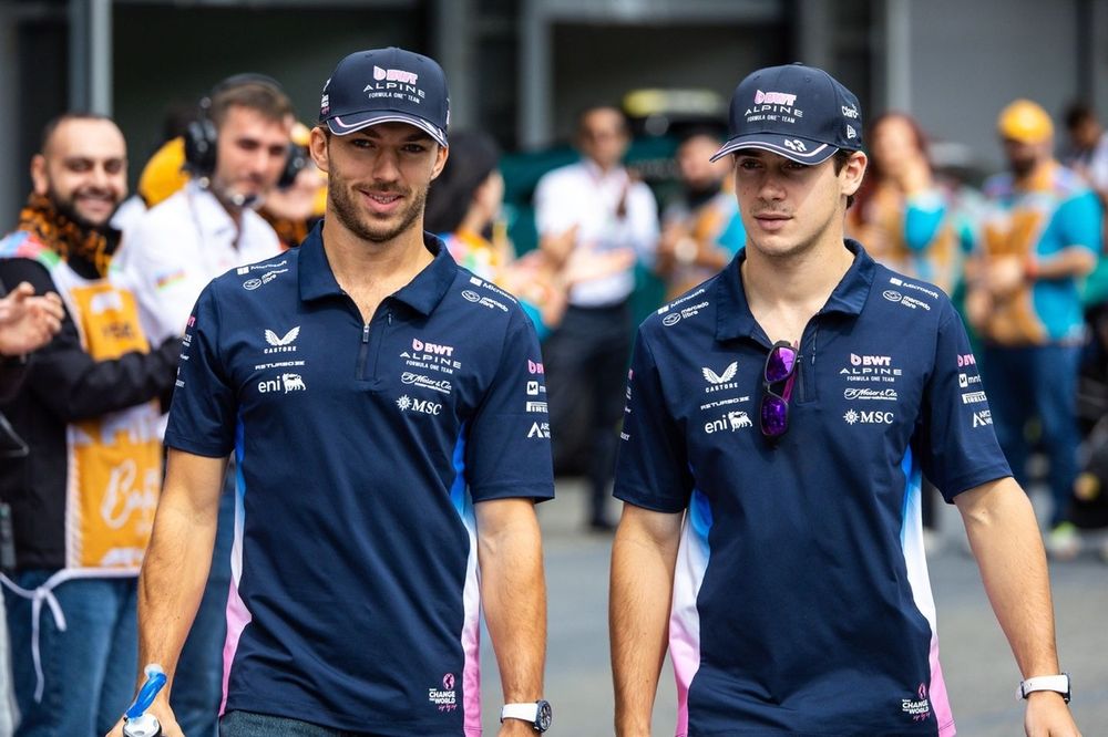 Two men in matching navy blue polo shirts with logos walking outdoors.