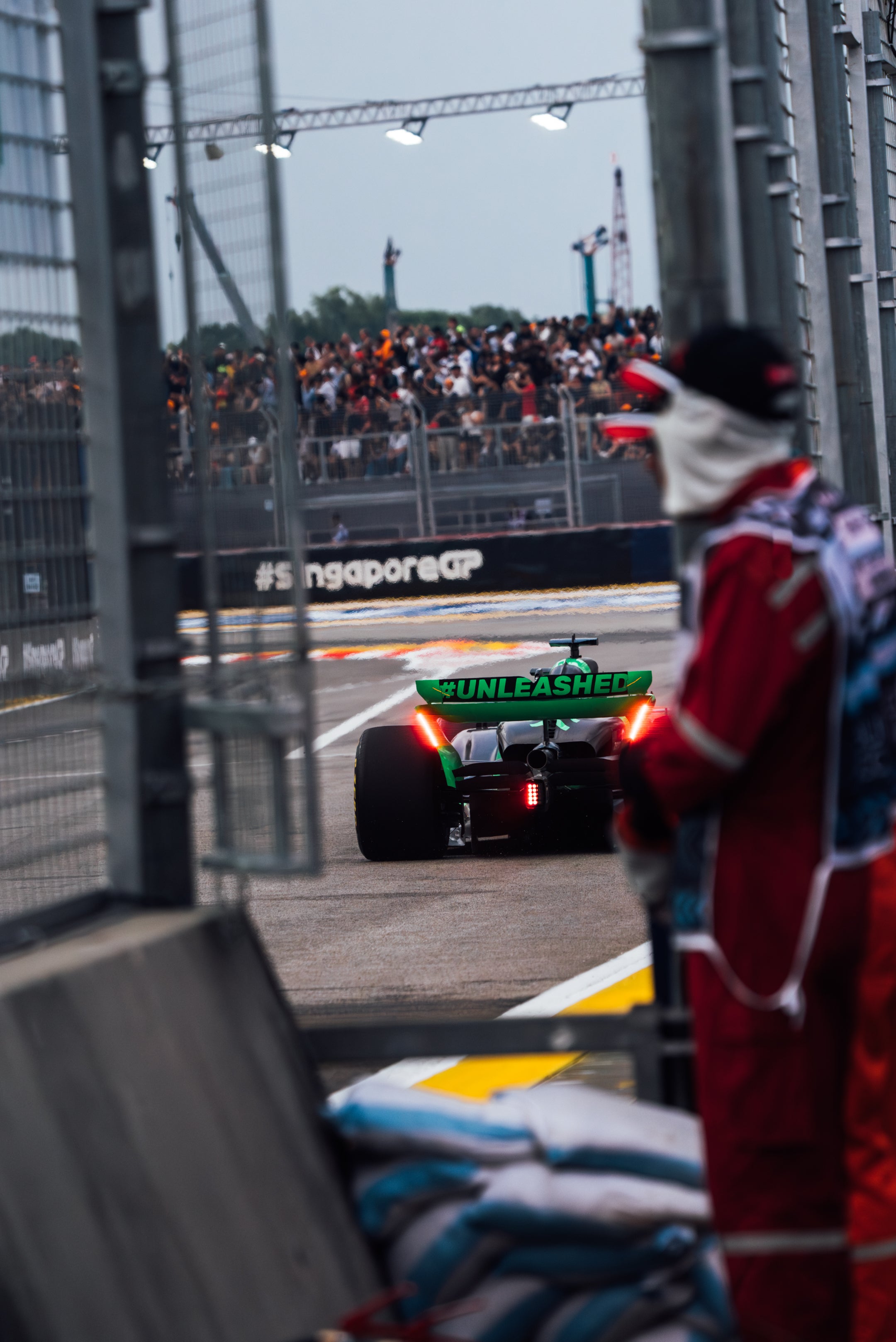 F1 car on a track with a person in racing gear and a crowd in the background