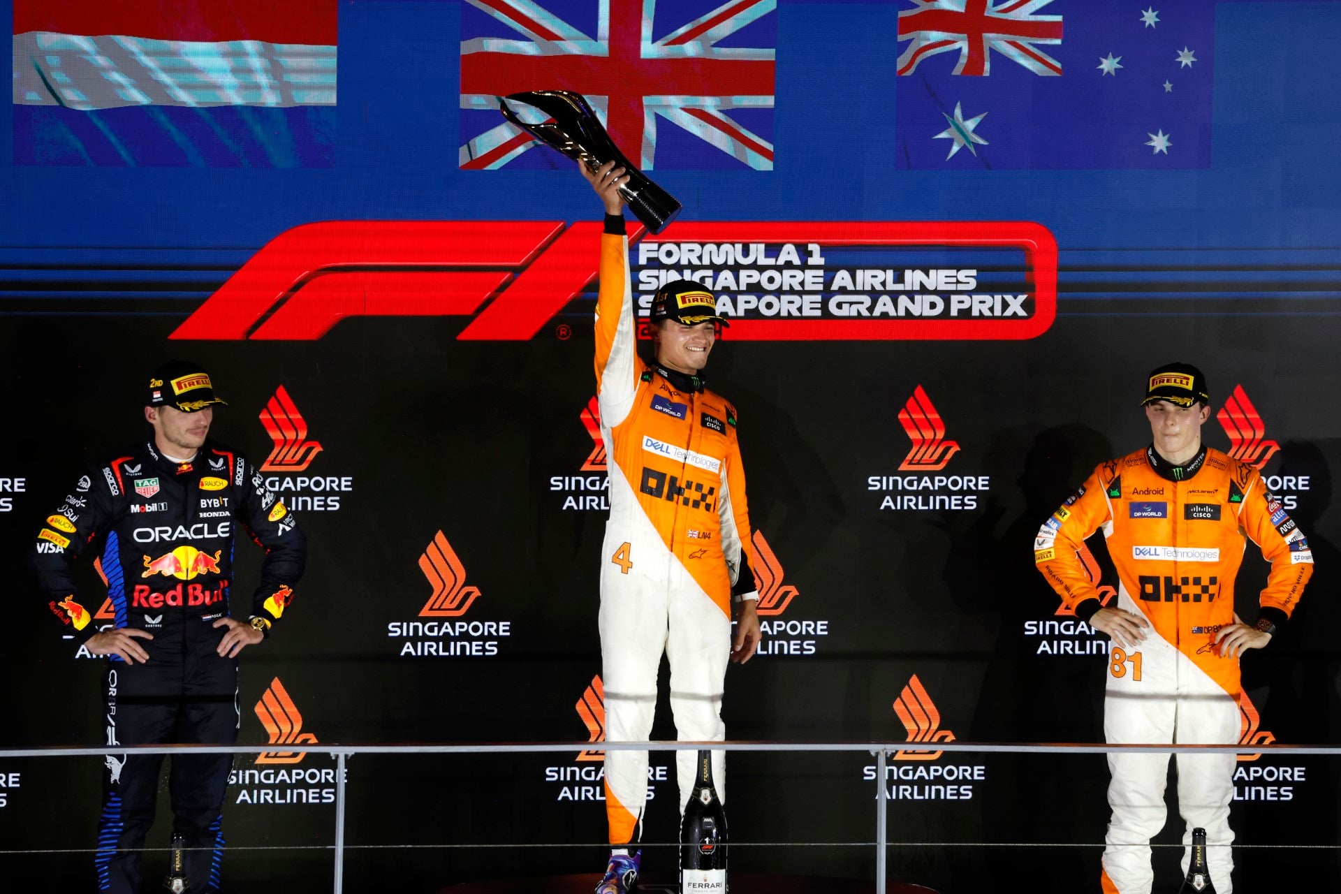 Three Formula 1 drivers on a podium with Singapore Airlines branding