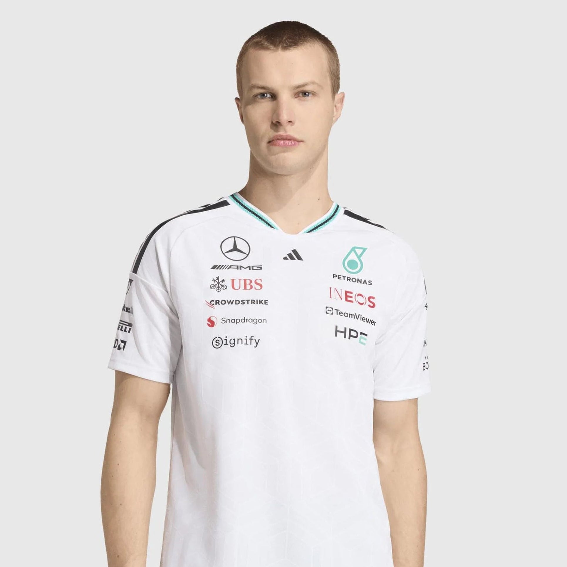 Person wearing a white sports jersey with various sponsor logos on a light gray background